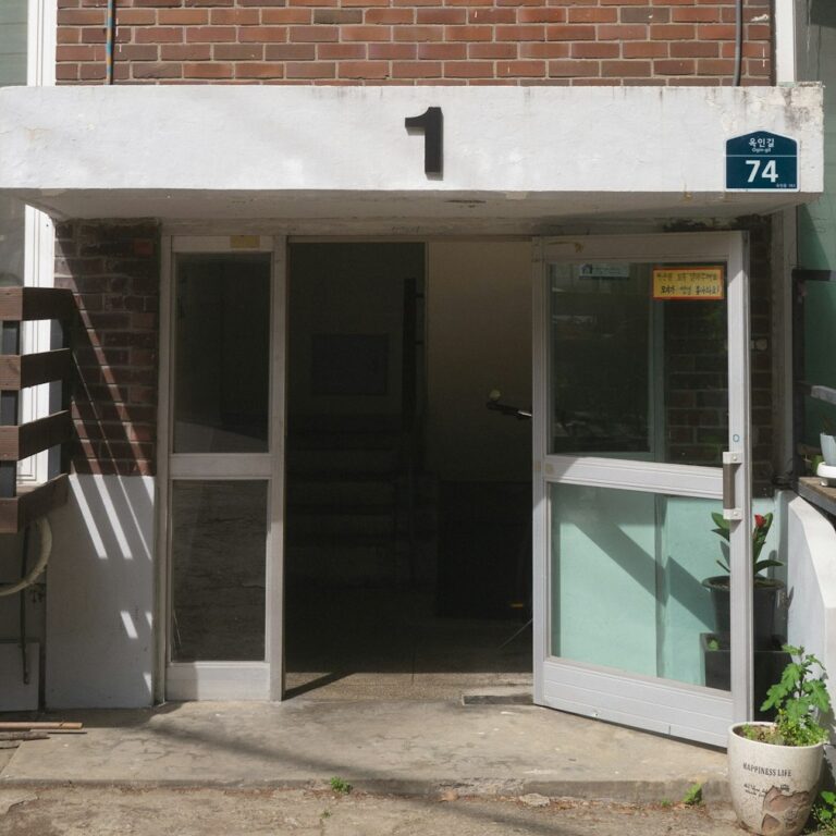 The entrance of a small Korean multi-family villa, with a Korean street-name plate beside the door