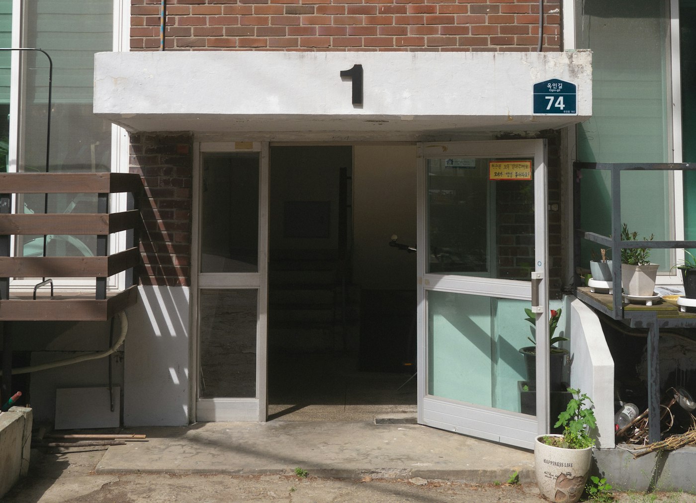 The entrance of a small Korean multi-family villa, with a Korean street-name plate beside the door