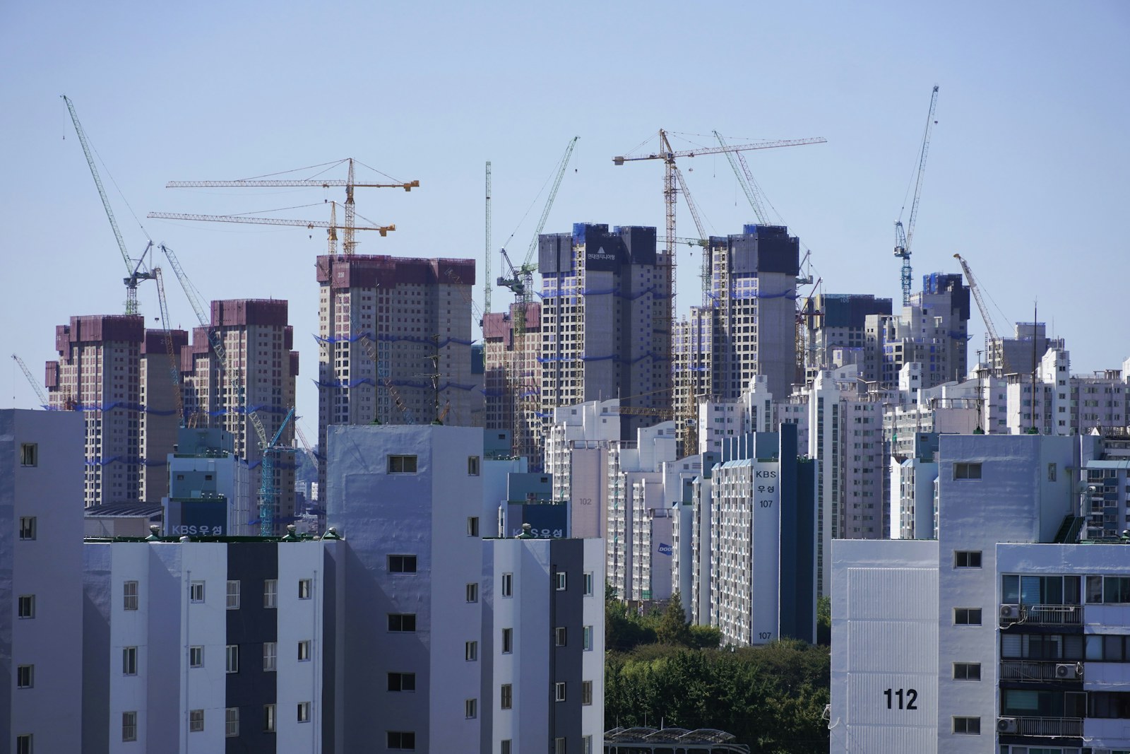 Numbered apartment blocks and construction cranes in a Korean city