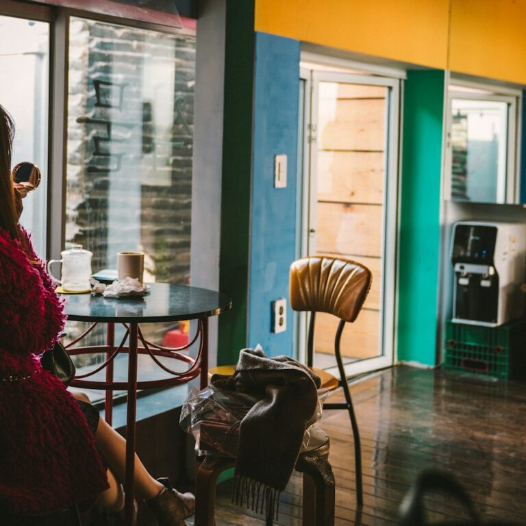 A woman sitting alone with coffee at a window table in a Seoul cafe