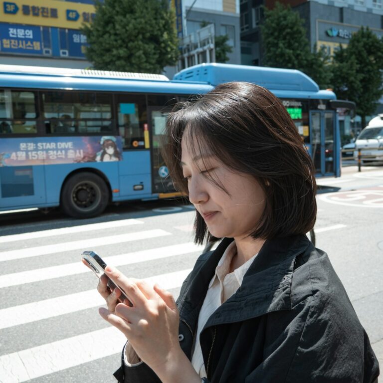 A woman checking her phone at a crosswalk in Seoul